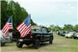 black truck decorated two American flags drive through the parking lot
