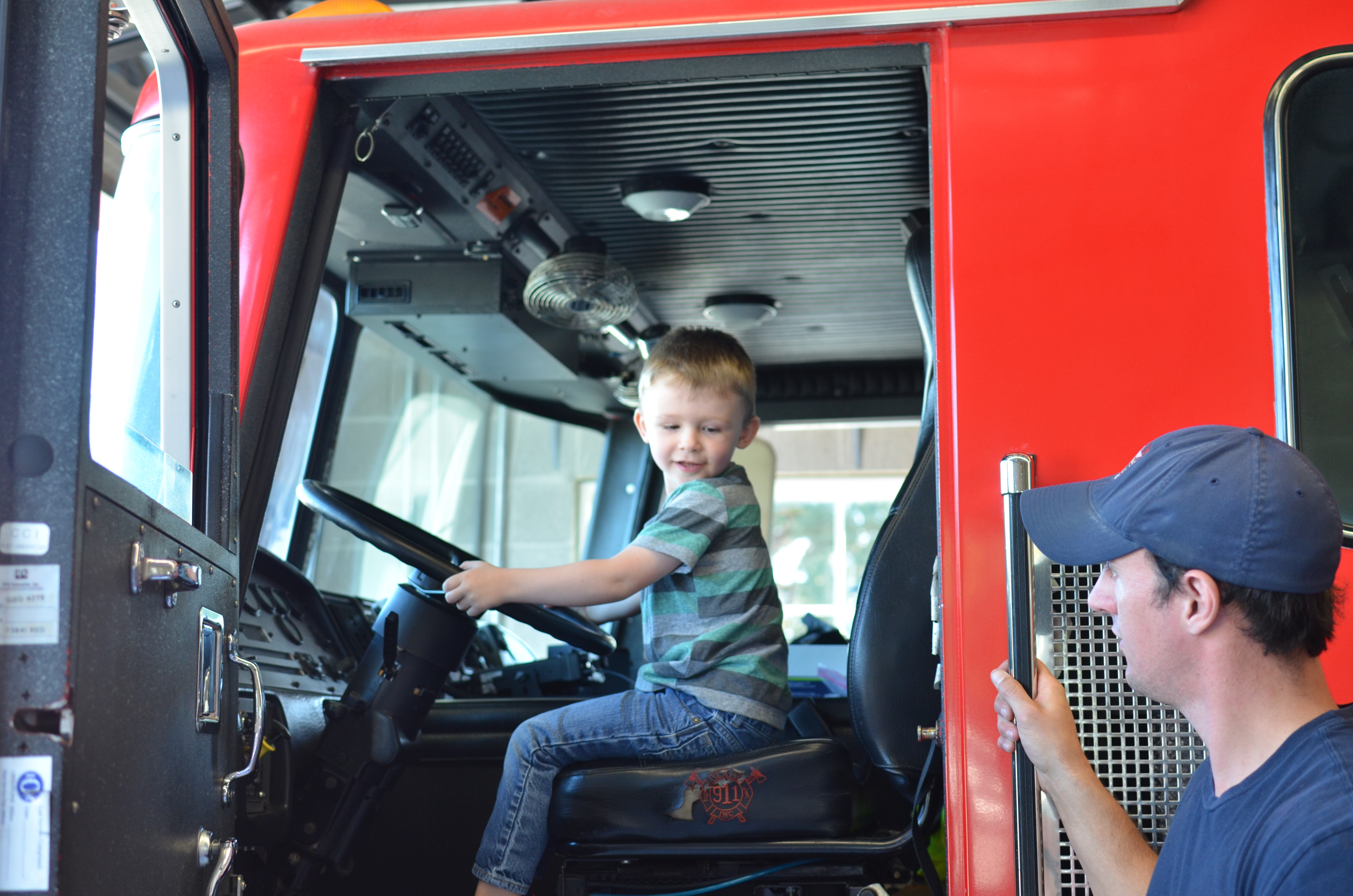 young boy sitting in driver's seat of fire truck