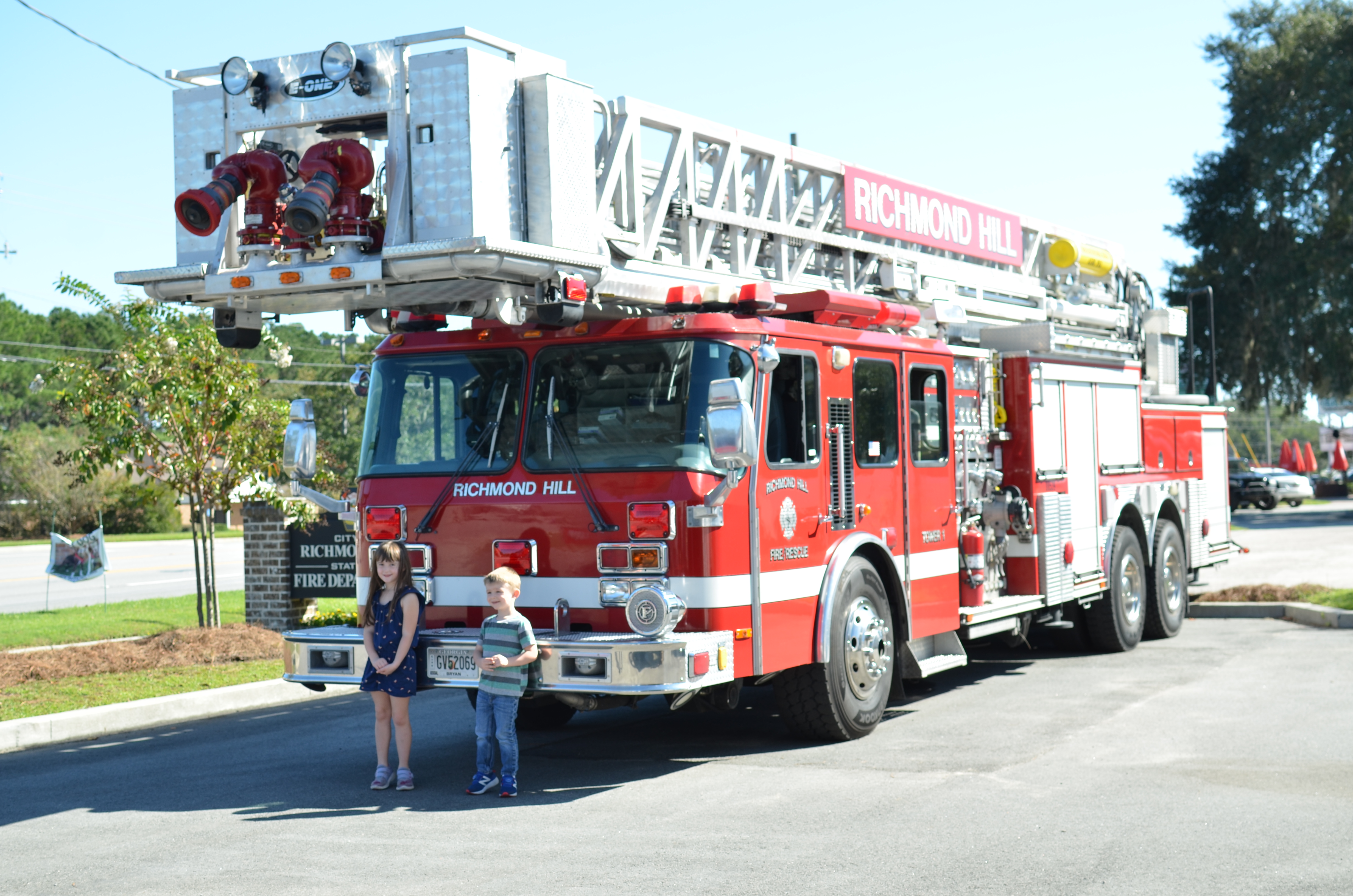 two children standing under fire truck ladder