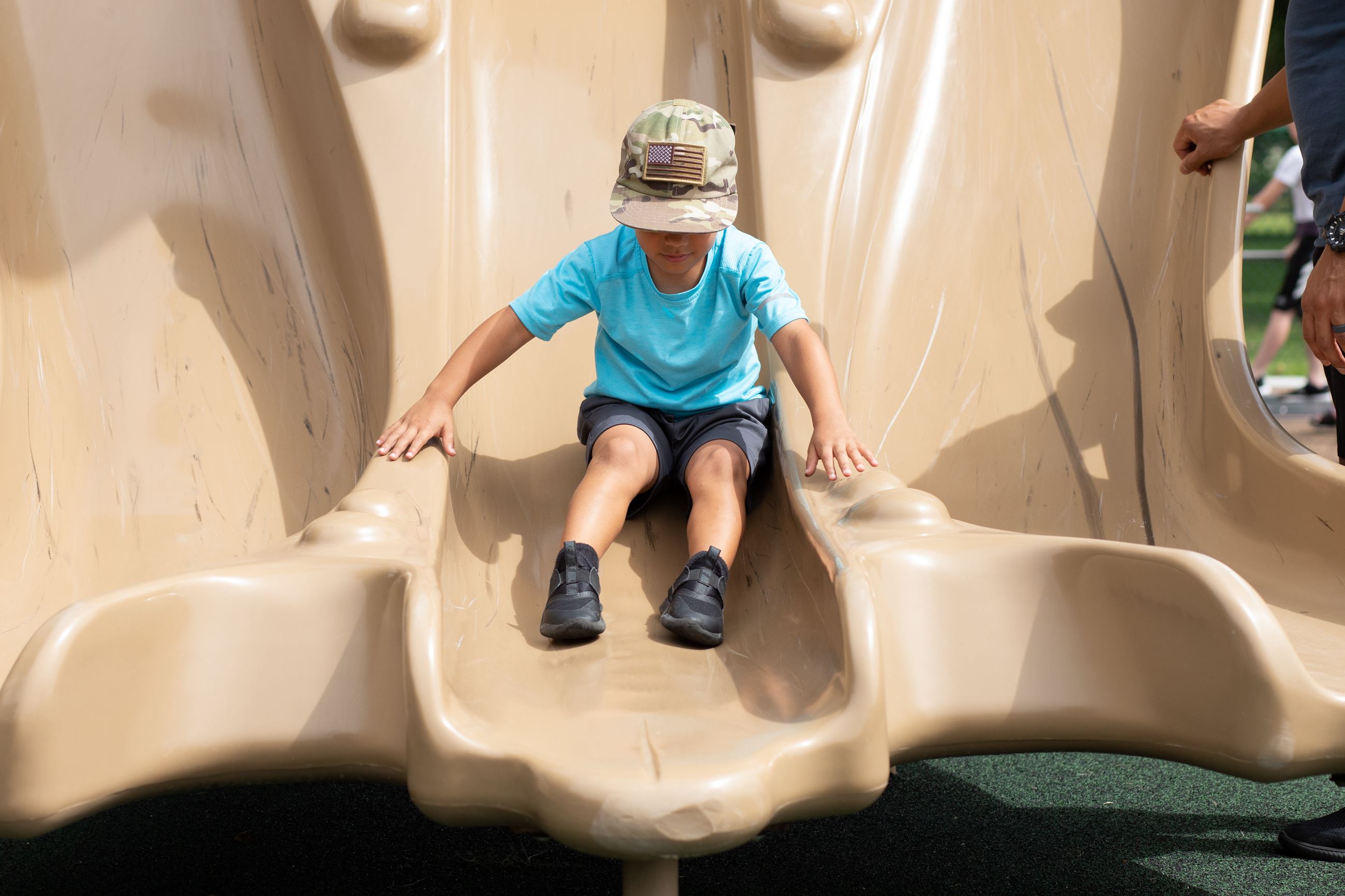 boy in blue shirt reaches bottom of slide