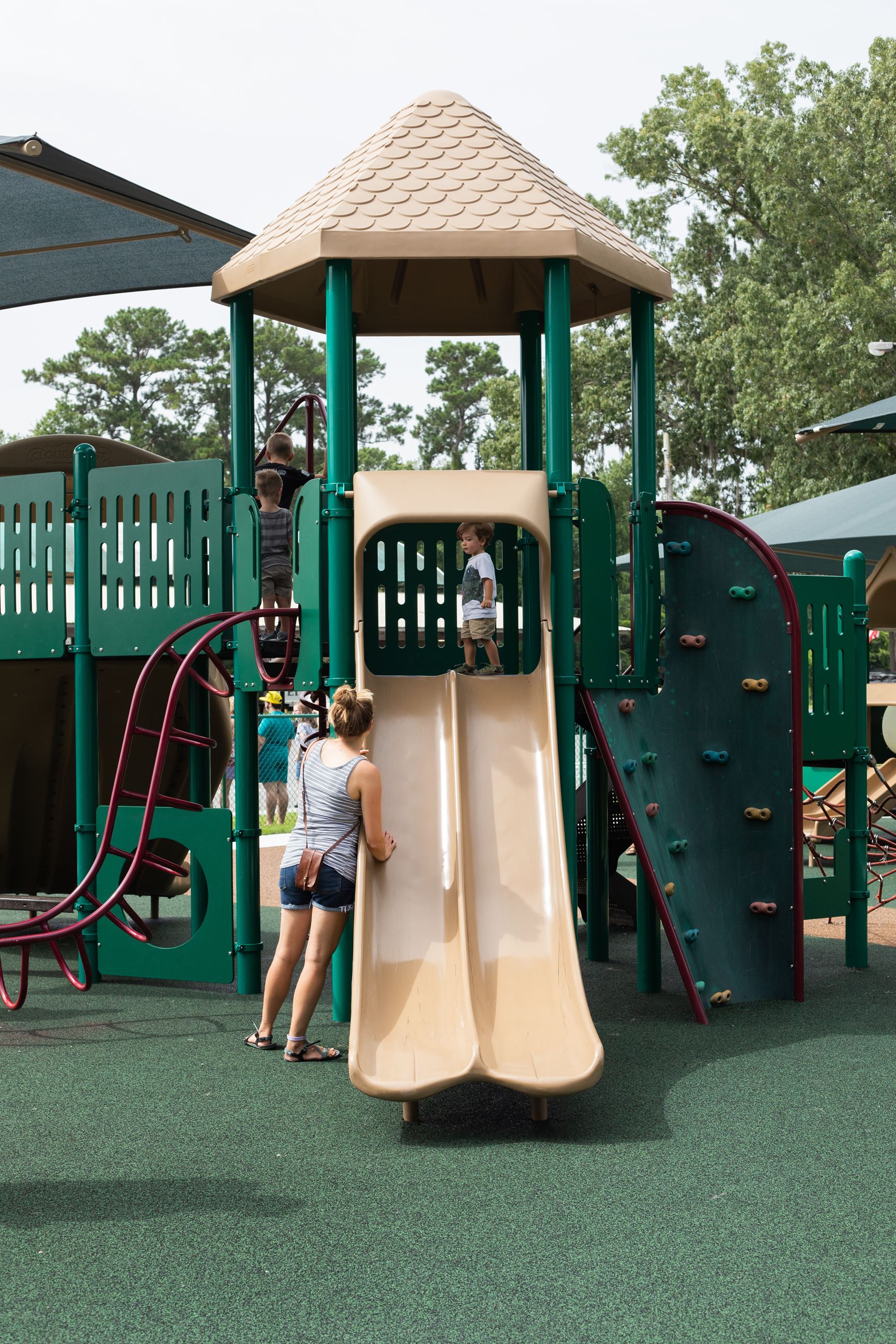 mother watches as boy slides down tan slide