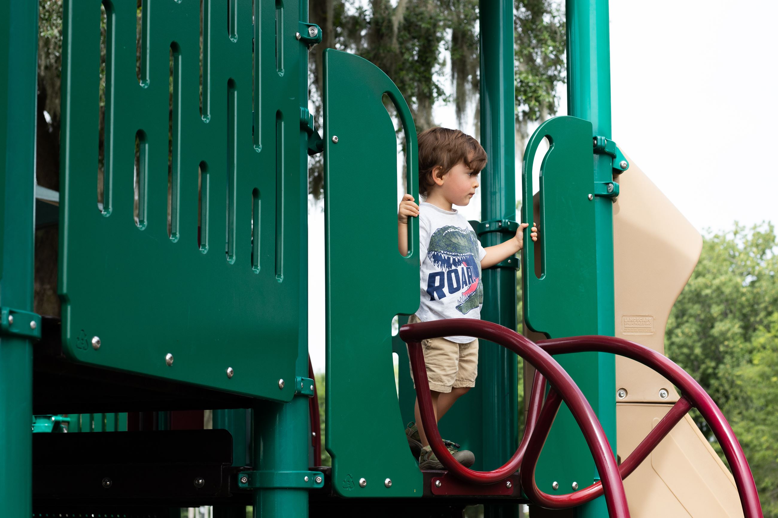 boy standing at top of playground slide