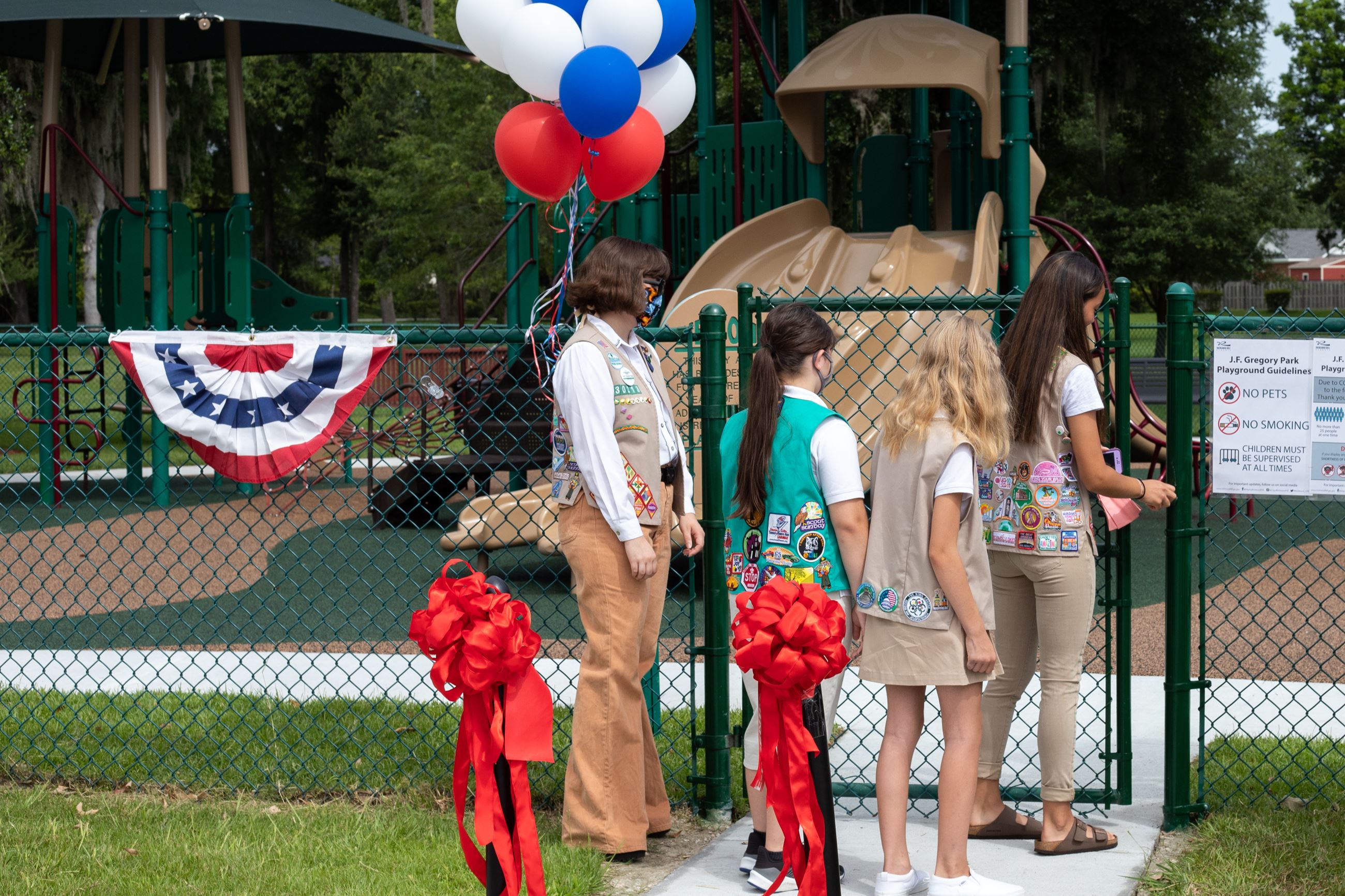 girl scout members opening park gate 